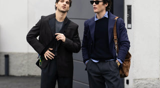 Two men in stylish men's fashion outfits with blazers and slacks, standing outside