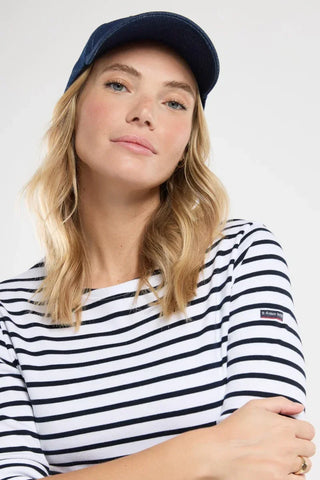 Woman in navy cap and white navy striped top with Armor Lux patch, nautical style fashion.