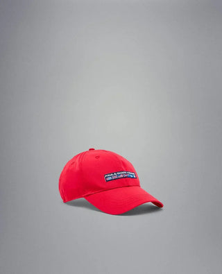 Red nylon yachting cap with embroidered patch and nautical flags on a gray background