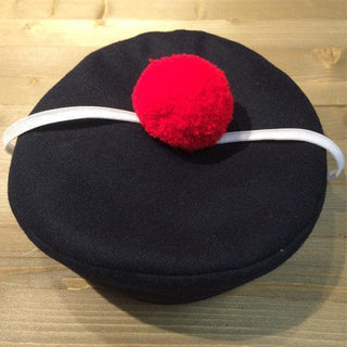 Navy blue French sailor bachi hat with red pompom and white strap on wooden surface