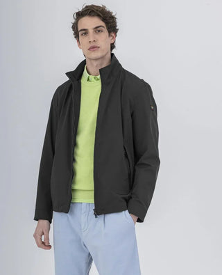 Man wearing a black nylon jacket over a light green sweater and light blue pants