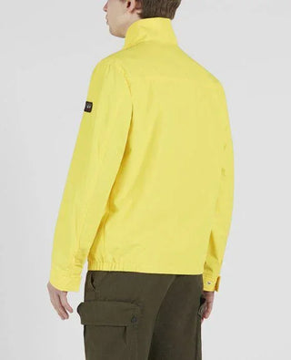Man wearing yellow nylon Typhoon jacket, back view, with olive cargo pants