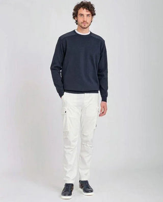 Man wearing navy crew neck sweater with shoulder patches and white cargo pants