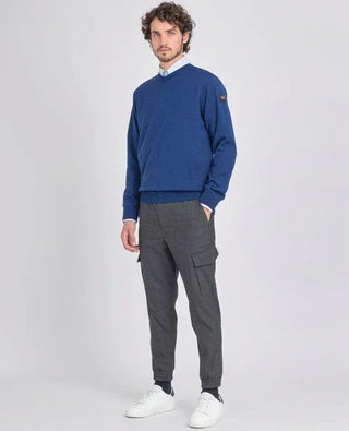 Man wearing a blue V-neck merino wool sweater, grey cargo pants, and white sneakers