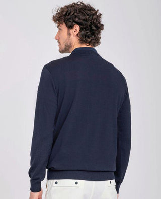 Man wearing a dark navy merino wool sweater and white pants, seen from the back