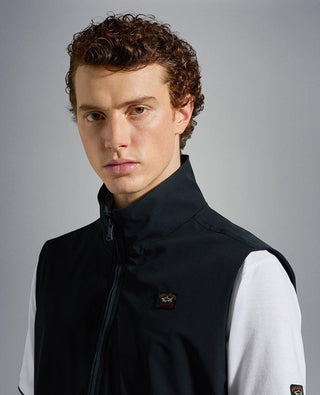 Man wearing sleeveless navy nylon vest with zip and embroidered chest logo