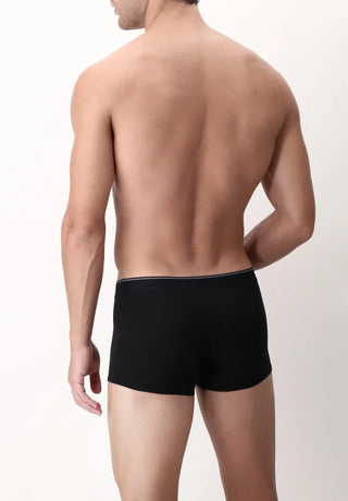 Male model wearing black boxer briefs, rear view, against plain light background
