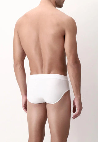 Man wearing white classic brief underwear, back view, against plain background